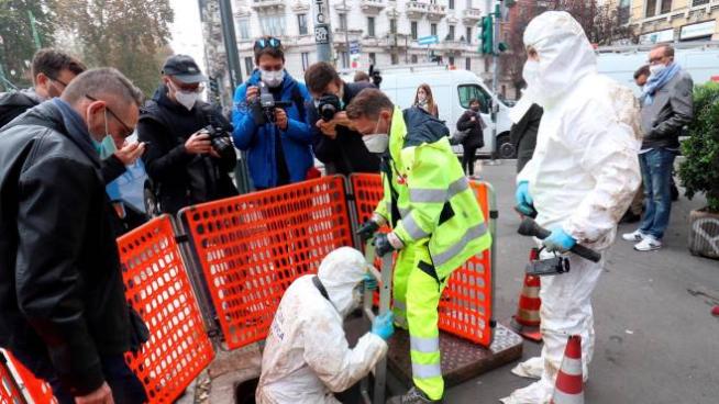 Uomini della polizia scientifica scendono all'interno del tombino in piazza Ascoli