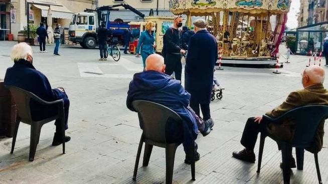 Gli anziani con le sedie in piazza